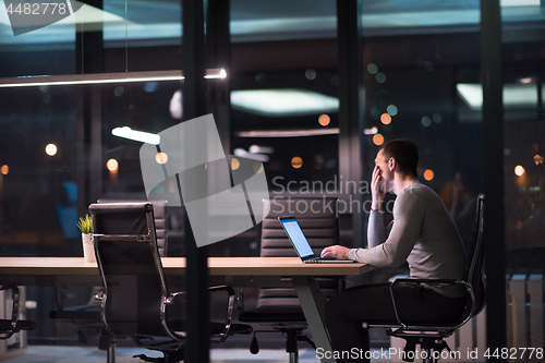 Image of man working on laptop in dark office