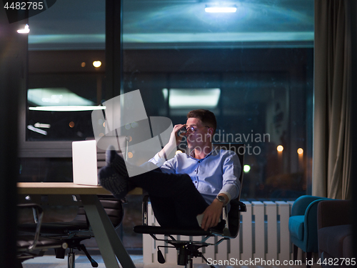 Image of businessman sitting with legs on desk at office