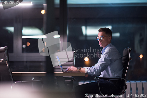 Image of man working on laptop in dark office