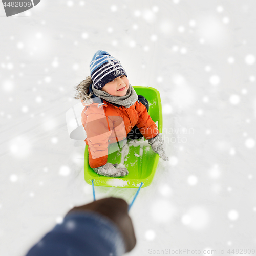 Image of happy boy riding sled on snow in winter