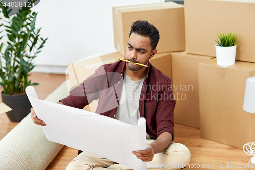 Image of man with blueprint and boxes moving to new home