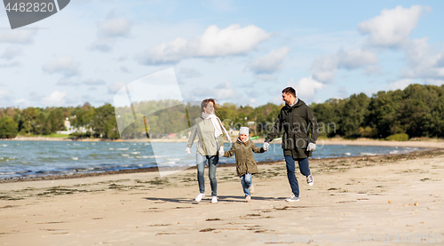 Image of happy family running along autumn beach