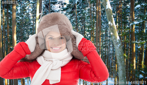 Image of happy woman in fur hat over winter forest