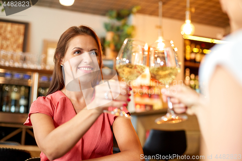 Image of happy women drinking wine at bar or restaurant