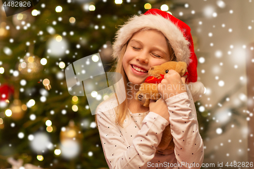 Image of smiling girl in santa hat with christmas gift