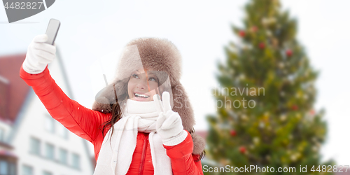 Image of woman taking selfie over christmas tree
