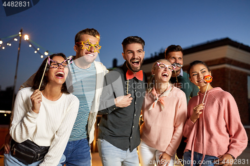 Image of happy friends with party props at rooftop