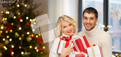 Image of happy couple with christmas gifts at home