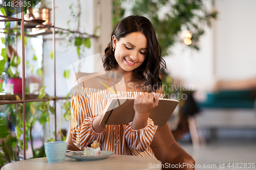 Image of happy woman with notebook at coffee shop or cafe