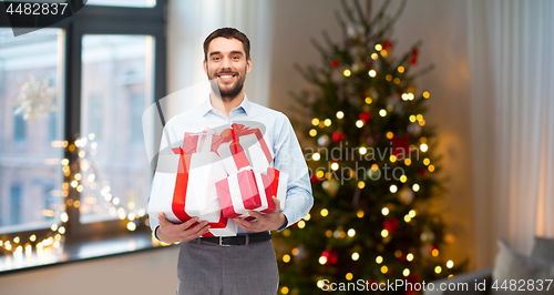 Image of happy man with christmas gifts at home