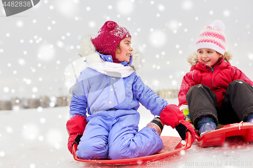 Image of happy little girls on sleds outdoors in winter