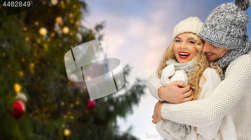 Image of happy couple hugging over christmas tree