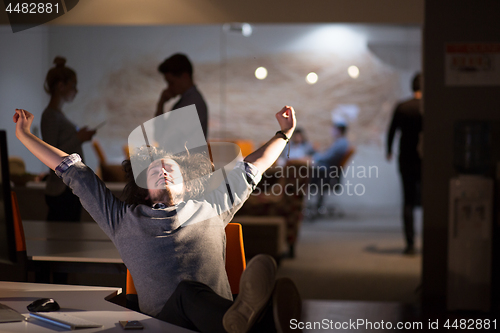 Image of businessman sitting with legs on desk at office