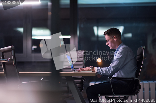 Image of man working on laptop in dark office