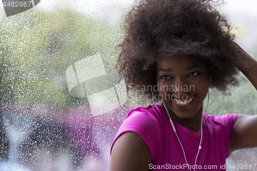 Image of portrait of young afro american woman in gym while listening mus