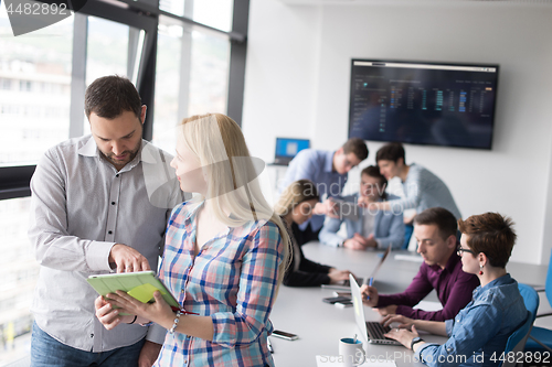 Image of Two Business People Working With Tablet in office