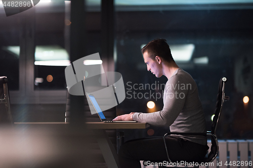 Image of man working on laptop in dark office