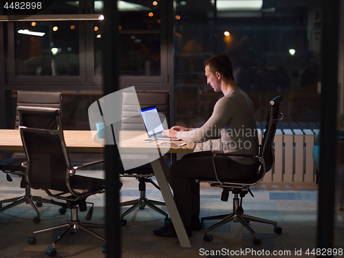 Image of man working on laptop in dark office