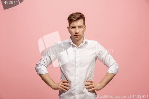 Image of The serious businessman standing and looking at camera against pink background.