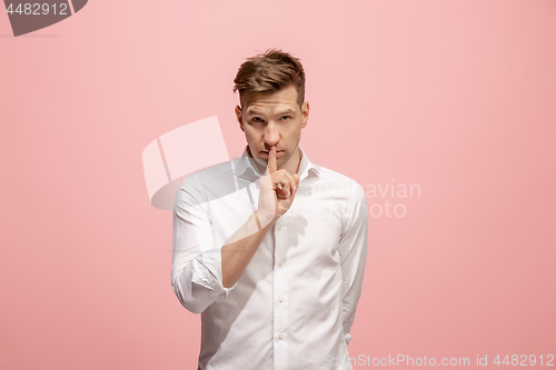 Image of The young man whispering a secret behind her hand over pink background