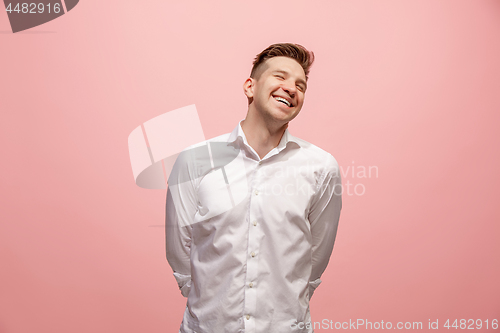 Image of The happy business man standing and smiling against pink background.