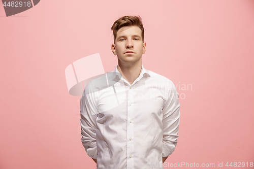 Image of The serious businessman standing and looking at camera against pink background.