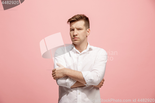 Image of The serious businessman standing and looking at camera against pink background.