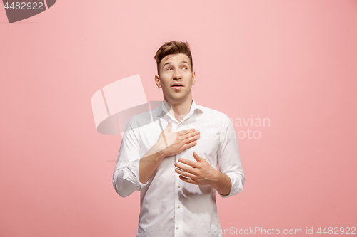 Image of Beautiful male half-length portrait isolated on pink studio backgroud. The young emotional surprised man