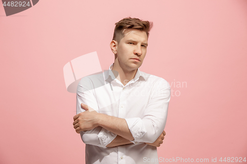 Image of The serious businessman standing and looking at camera against pink background.