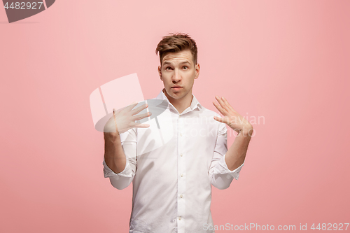 Image of Beautiful male half-length portrait isolated on pink studio backgroud. The young emotional surprised man