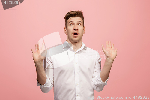 Image of Beautiful male half-length portrait isolated on pink studio backgroud. The young emotional surprised man