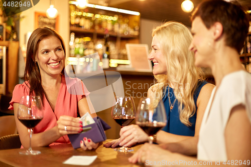 Image of women paying bill at wine bar or restaurant