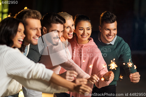 Image of happy friends with sparklers at rooftop party