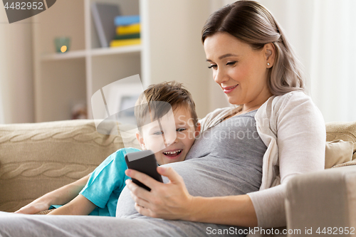 Image of pregnant mother and son with smartphone at home