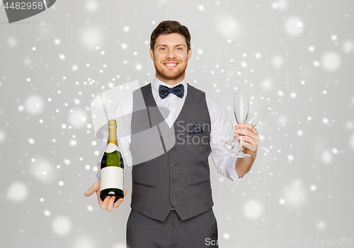 Image of man with bottle of champagne and glasses at party