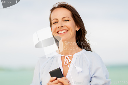 Image of happy woman with smartphone on summer beach