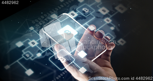 Image of close up of hand with smartphone and bitcoin