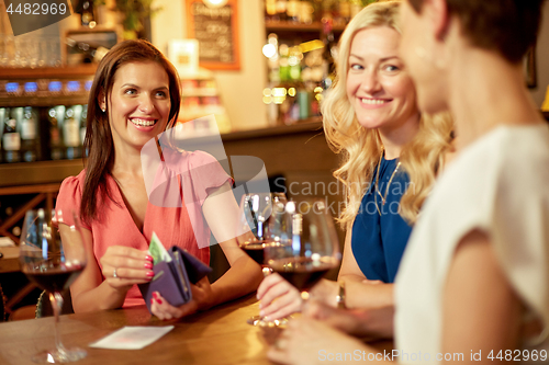 Image of women paying bill at wine bar or restaurant