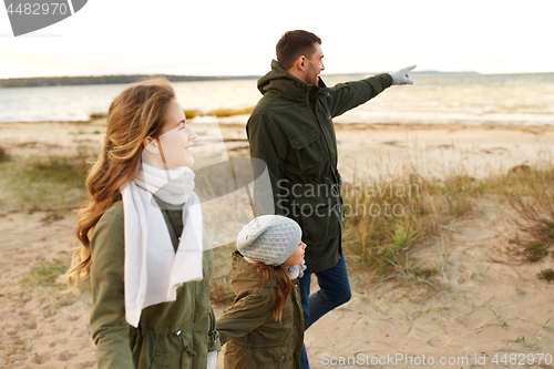 Image of happy family walking along autumn beach