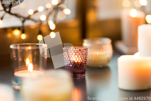 Image of candles burning on window sill with garland lights