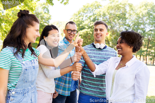 Image of happy friends making thumbs up in park