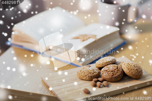 Image of oatmeal cookies, almonds and book on table at home