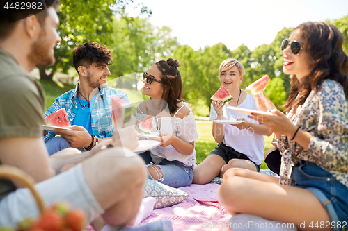 Image of happy friends eating watermelon at summer picnic