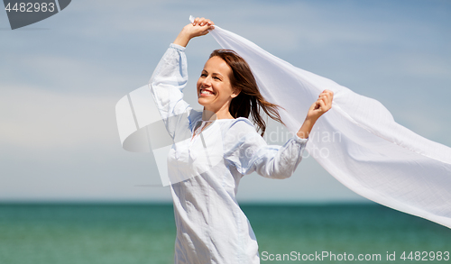 Image of happy woman with shawl waving in wind on beach