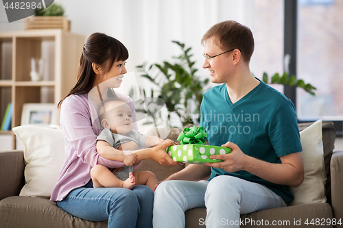 Image of mother with baby giving birthday present to father