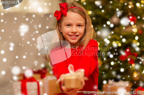 Image of smiling girl with christmas gift at home