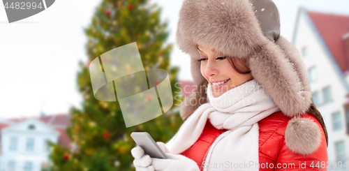 Image of woman with smartphone over christmas tree