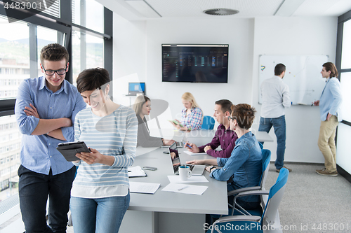 Image of Two Business People Working With Tablet in office