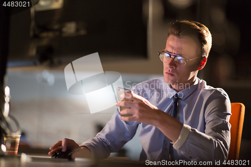 Image of man using mobile phone in dark office