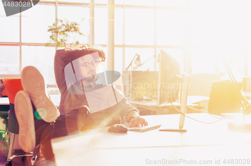 Image of businessman sitting with legs on desk